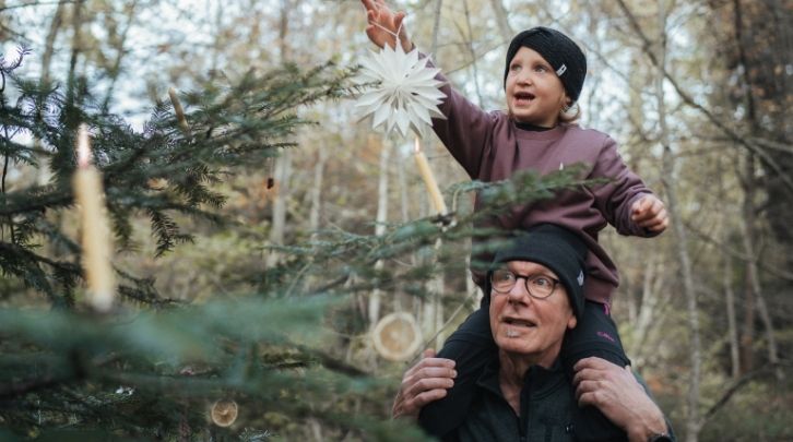 Ein Grossvater und eine Enkelin schmücken den Weihnachtsbaum.
