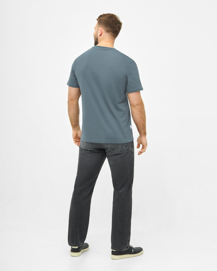 NIKIN TreeShirt Steel Blue Herren-T-Shirt, Rückansicht, kombiniert mit schwarzen Jeans und schwarzen Schuhen.