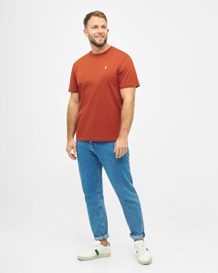 NIKIN TreeShirt Brick für Herren, Farbe Rost, mit blauen Jeans und weißen Sneakern vor weissem Hintergrund.