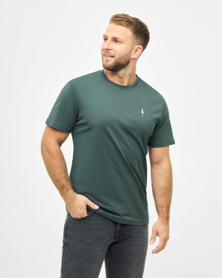 NIKIN TreeShirt Herren T-Shirt, grün, aus Bio-Baumwolle, mit Rundhalsausschnitt, kombiniert mit dunkler Jeans.