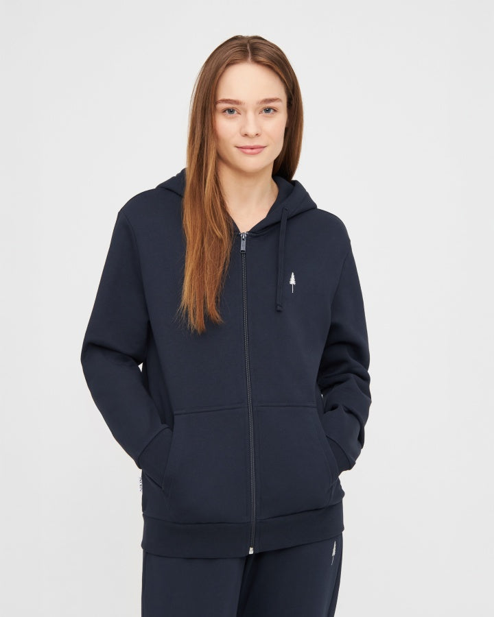 NIKIN TreeHoodie-Jacke in Dunkelblau, Unisex-Kapuzenjacke, lange braune Haare, Hände in den Taschen.