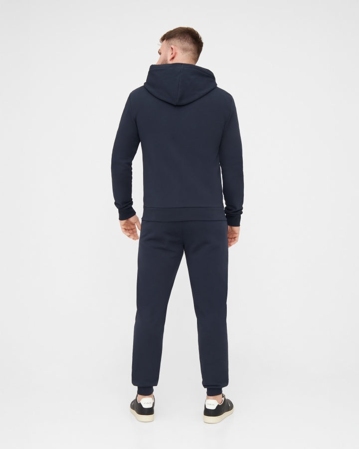 NIKIN TreeHoodie-Jacke in Dunkelblau und dazu passende Jogginghose, Mann von hinten vor weißem Hintergrund.