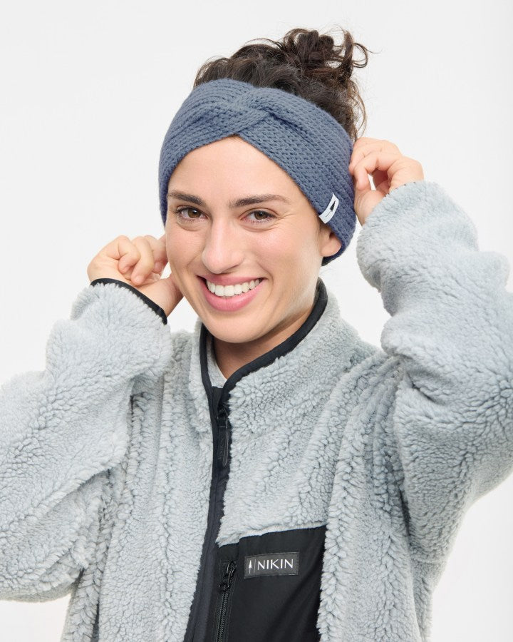 NIKIN TreeHeadband Bandeau en tricot torsadé, Cosy, Farbe Steel Blue, gestrickt, Damen-Modell vor weißem Hintergrund.