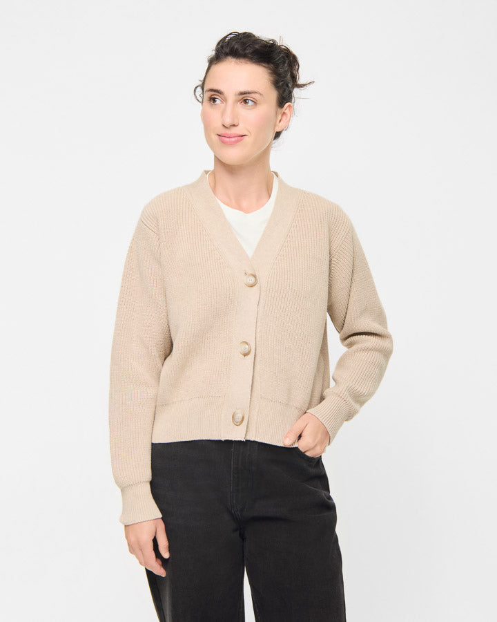 NIKIN TreeCardigan Damen-Strickjacke in Beige, langärmelig, kombiniert mit einem weißen Oberteil und einer schwarzen Hose.