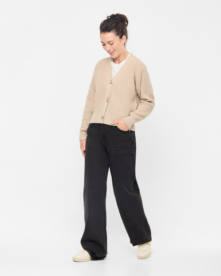 NIKIN TreeCardigan : cardigan pour femme beige, associé à un t-shirt blanc, un pantalon large noir et des chaussures couleur crème.