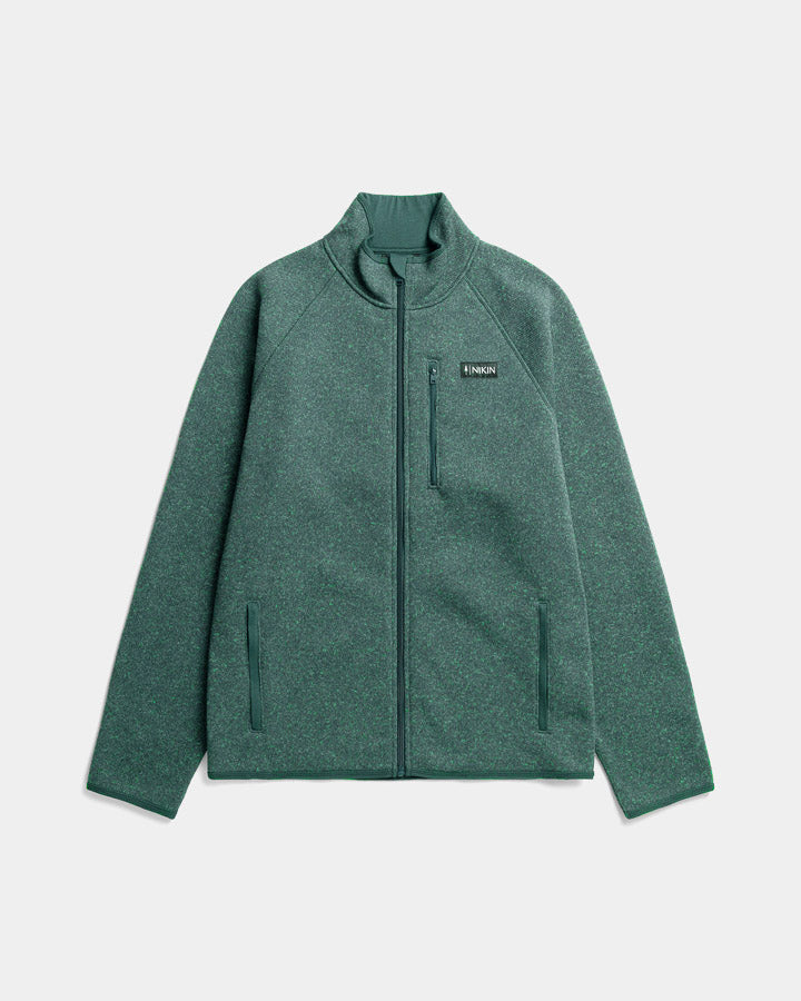 The Nature Nomad TreeJacket is a green zip-up fleece with a stand collar, zippered chest pocket, two side pockets, and a small left-chest logo—an eco-friendly jacket shown flat on a light gray background.