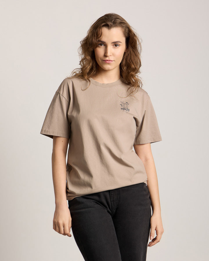NIKIN TreeShirt Out Of Office Relaxed Taupe Damen T-Shirt, welliges braunes Haar, einfarbiger Hintergrund.