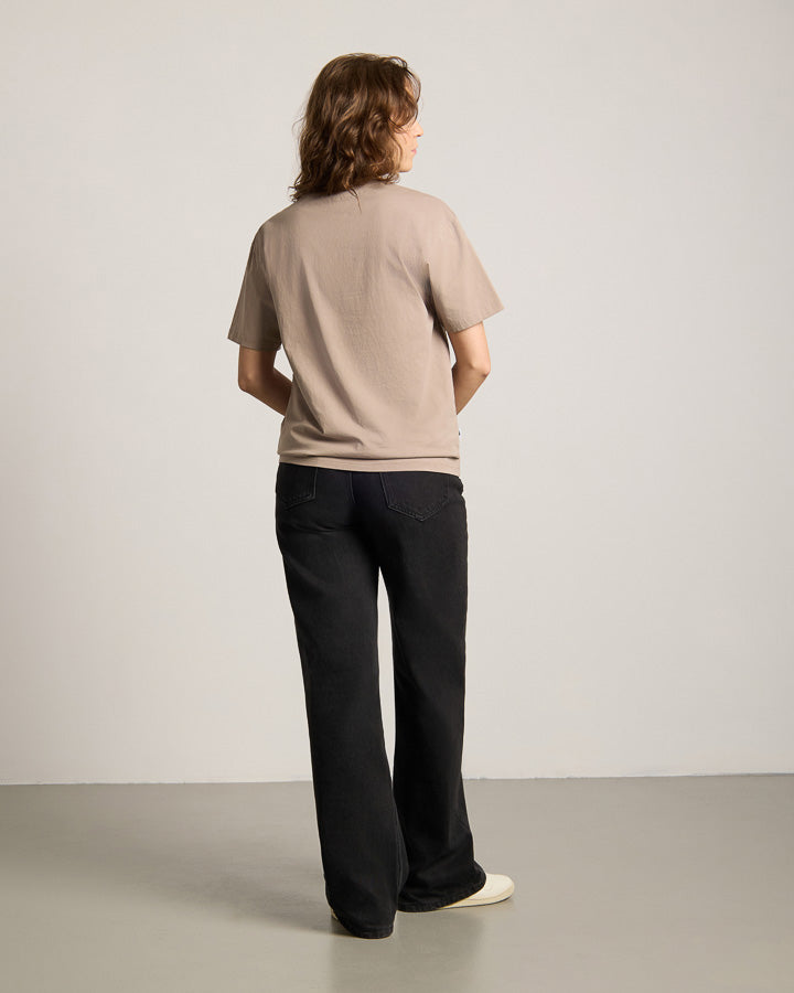 NIKIN TreeShirt Out Of Office Relaxed Taupe T-Shirt, Unisex, Farbe Taupe, kombiniert mit schwarzen Hosen auf grauem Boden.