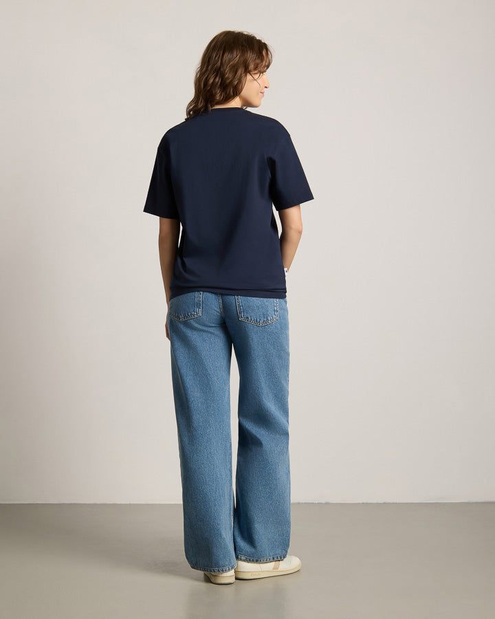 NIKIN TreeShirt Pale Blue Dot Relaxed Dark Navy, T-Shirt, Unisex, kombiniert mit blauen Wide-Leg-Jeans.