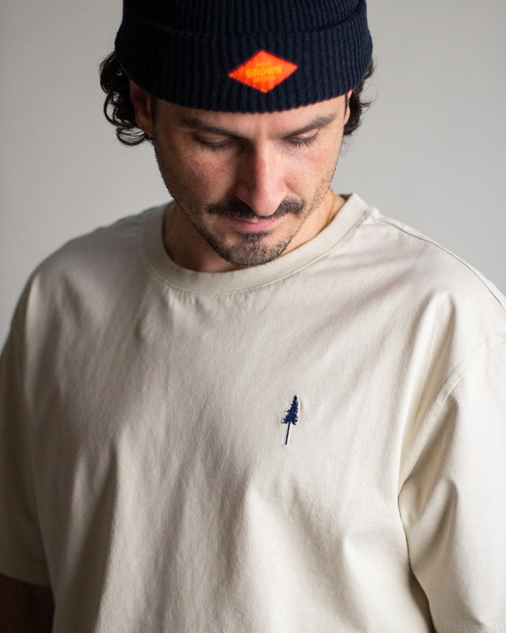NIKIN TreeShirt Anniversary Relaxed T-Shirt in der Farbe „Pumice“, Herrenmodell mit schwarzer Mütze, neutraler Gesichtsausdruck.