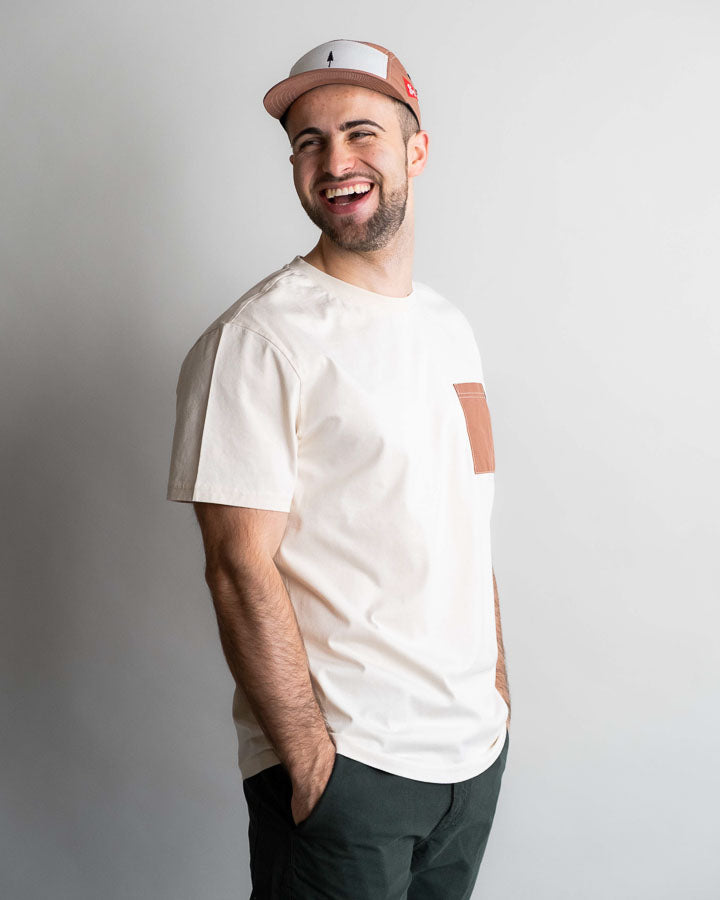 NIKIN T-shirt pour homme TreeShirt Pocket Spatz Chalk, avec poche poitrine, porté par un homme coiffé d'une casquette sur fond clair.