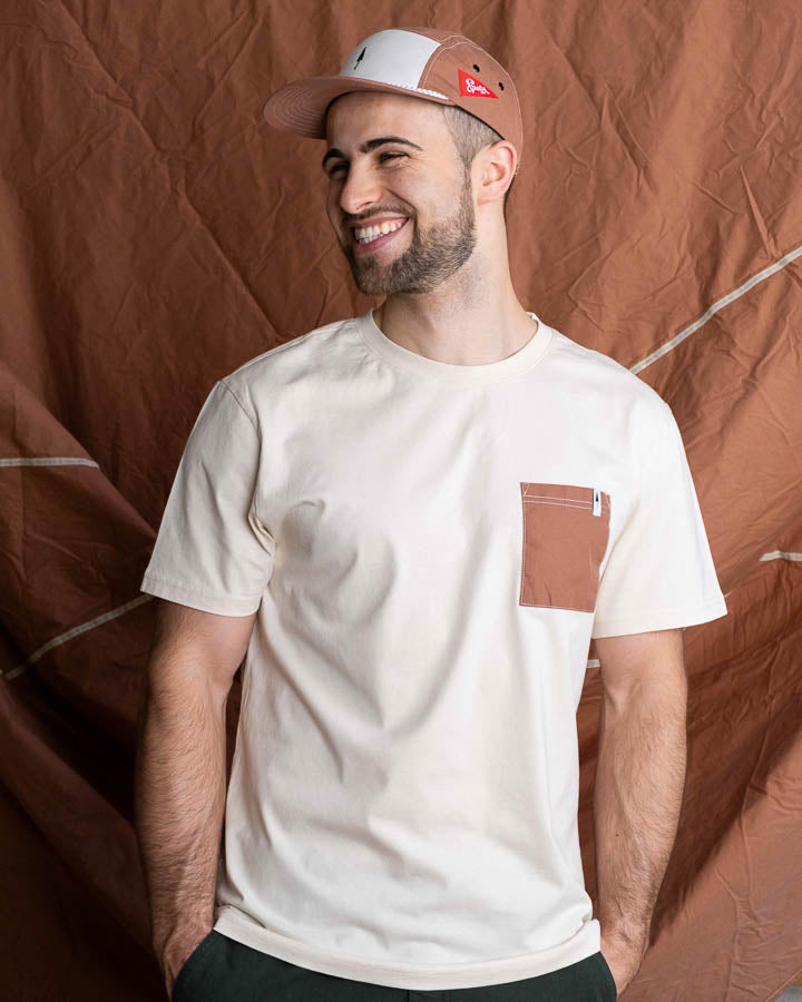 NIKIN TreeShirt Pocket Spatz Chalk Herren-T-Shirt, Farbe Chalk, mit Brusttasche, vor braunem Hintergrund.