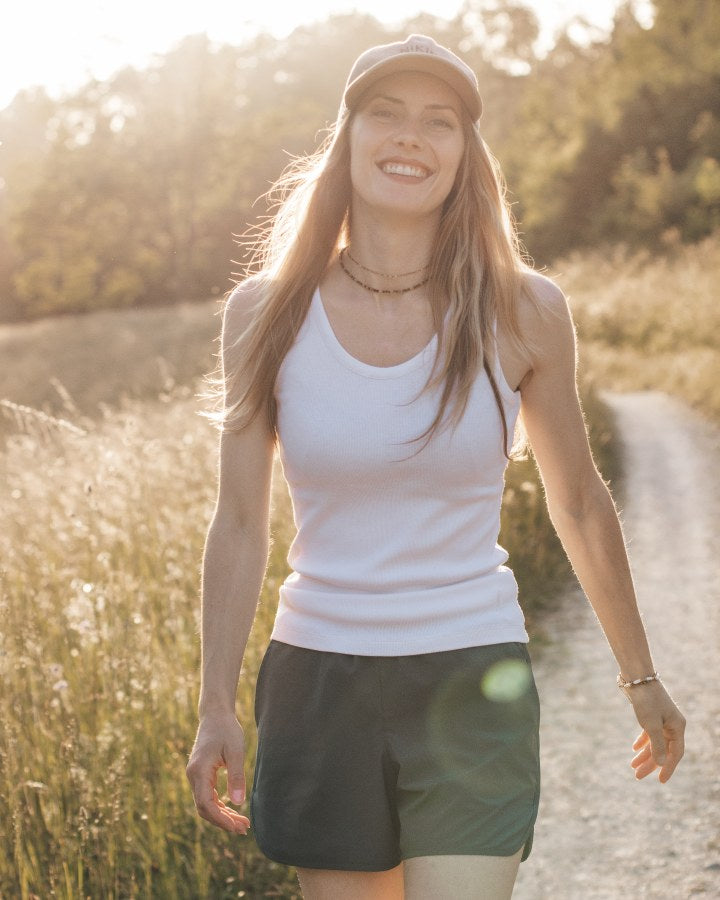 NIKIN TreeTop Damen-Shorts „Snow White“, Baumwolle, sommerlich, mit Mütze, auf einem sonnigen Wiesenweg.